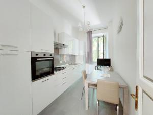 eine Küche mit weißen Schränken und einem Tisch mit Stühlen in der Unterkunft 4BNB - Luxury Mazzini Apartment in Rom
