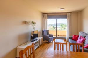 Una sala de estar con un sofá y una mesa con televisión. en Residencial Pinamar, en Sanxenxo