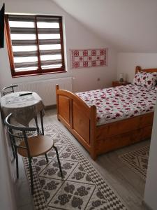 a bedroom with a bed and a table and a chair at Kalotaszeg Vendégház in Izvoru Crişului