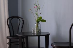 a vase with flowers on a table with two chairs at Camp Järvsö Hotell in Järvsö