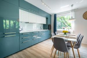 uma cozinha com armários azuis e uma mesa com cadeiras em Sun House Apartment + free parking em Breslávia
