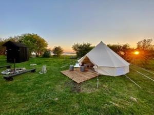 a white tent in a field with the sun setting at Abruka Glamping in Abruka