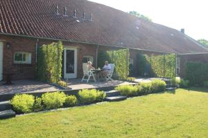 two people sitting at a table outside of a house at B&B De Oldambtster in Beerta
