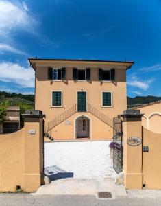 a large yellow house with a staircase in front of it at Garden Relays Villa Rosy in Massarosa