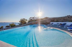 a large swimming pool with the sun in the background at Agnandi Cielo in Tourlos