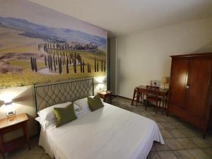 a bedroom with a white bed with a painting on the wall at Hotel Le Colline in San Gimignano