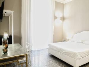 a white bedroom with a bed and a table at Palazzo La Piana Rooms in Catania