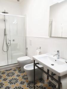 a white bathroom with a toilet and a sink at Palazzo La Piana Rooms in Catania