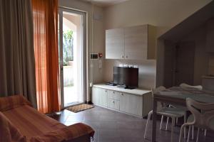 a room with a kitchen with a table and a television at Le Vele Residence in Pietra Ligure