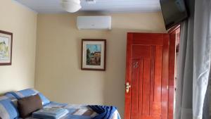 Cette chambre dispose d'une porte rouge et d'une télévision murale. dans l'établissement GARATUCAIA - Suites Casa de Madeira, à Angra dos Reis