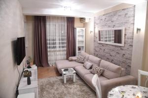 a living room with a couch and a brick wall at Lux Apartment Rose in Kragujevac