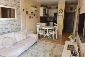 Una sala de estar con un sofá blanco y una mesa. en Lux Apartment Rose, en Kragujevac