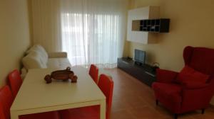 uma sala de estar com uma mesa e cadeiras vermelhas em Nova Almenara. Ideal para familias em Barrio-Mar