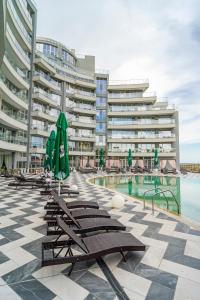 a row of lounge chairs with umbrellas next to a pool at Aparthotel Primorsko in Primorsko