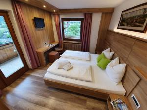 een slaapkamer met een groot bed met witte lakens en groene kussens bij Pension Tannenhof in San Giovanni in Val Aurina