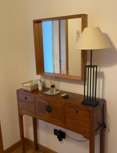 uma cómoda com um candeeiro e um espelho na parede em Apartamento en la playa em Ribeira