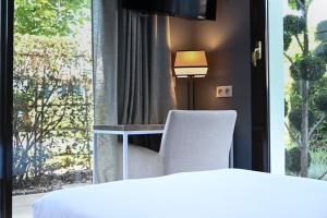a room with a bed and a chair and a window at Hôtel Les Muses in Annecy
