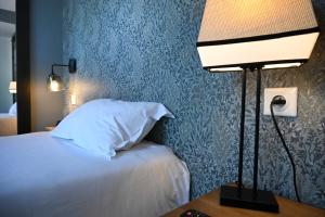 a bedroom with a bed and a lamp on a table at Hôtel Les Muses in Annecy