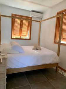 een bed in een slaapkamer met 2 ramen bij Villa GRENADINE Vue panoramique, les pieds dans l'eau in Terre-de-Haut