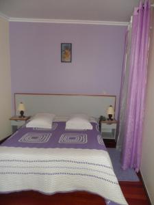 a bedroom with a large bed with purple curtains at Florinda in Chaves