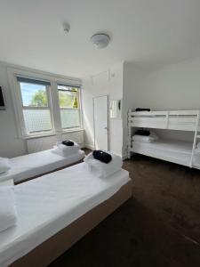 two beds in a white room with two windows at The Lodge in Bournemouth