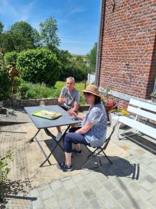 un hombre y una mujer sentados en una mesa de picnic en Maison de campagne avec superbe vue panoramique!, en Bousignies-sur-Roc