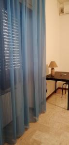 a room with blue curtains and a desk and a table at Sant'Ermete in Matino