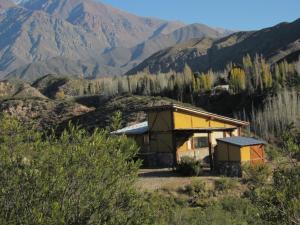 a small yellow building with mountains in the background at Cabaña La Mostacita - Complejo El Taller in Potrerillos