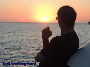 Ein Mann sitzt auf einem Boot und betrachtet den Sonnenuntergang. in der Unterkunft Hotel Marfil in Sant Antoni de Portmany