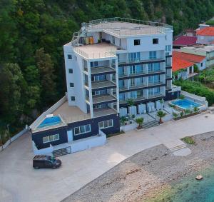 an apartment building with a car parked in front of it at Hotel Vienna in Herceg-Novi