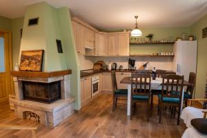 a kitchen with a fireplace and a table with chairs at Domek Leśny nad Tanwią in Koszele