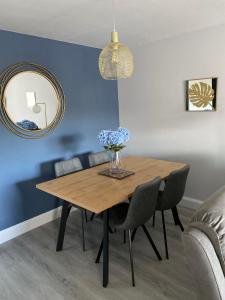 a dining room table with chairs and a vase of flowers at Causeway Coast Apartments Cora Marine in Ballycastle