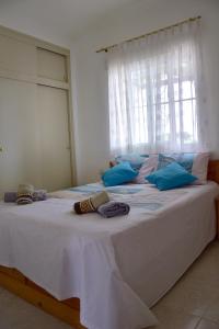a large white bed with blue pillows and a window at Casa Daguet in L'Eucaliptus