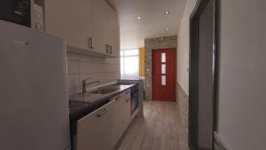 eine Küche mit einem Waschbecken und einer roten Tür in der Unterkunft Apartments Druzianic in Makarska