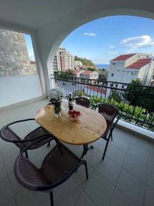 y balcón con mesa y sillas de madera. en Villa Mila, en Petrovac na Moru