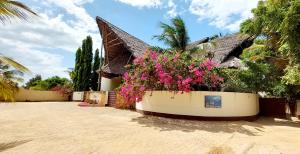 una casa con un plantador con flores rosas. en Kena Beach Hotel en Matemwe