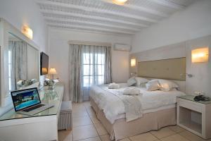 a bedroom with a bed and a laptop on a desk at Dionysos Luxury Hotel Mykonos in Ornos +34 photos