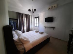 a bedroom with a bed with white sheets and a tv at Nerajoula House in Parga