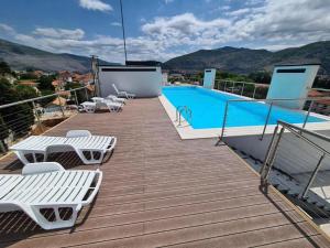 een terras met witte stoelen en een zwembad bij APARTMAN AURORA in Trebinje