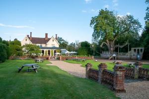 a house with a fence and a picnic table in the grass at The Oaksmere in Eye