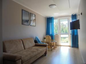 a living room with a couch and a sliding glass door at Apartament dwupokojowy 150 m do morza in Jarosławiec