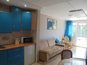 a kitchen and a living room with a couch and a microwave at Apartament dwupokojowy 150 m do morza in Jarosławiec