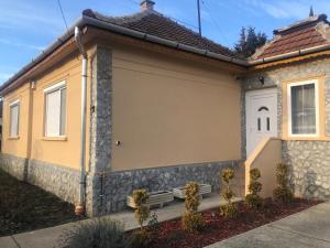 a house with a bench on the side of it at Törpi Apartman in Halmaj