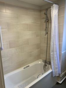 El baño incluye bañera blanca con cortina de ducha. en The Ivy en Lincolnshire