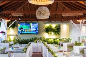 un ristorante con tavoli bianchi e una TV a parete di Almira Hotel a Troulos