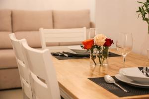 una mesa de madera con platos, vasos y flores. en Brasov Studio, en Brasov 3 fotos más
