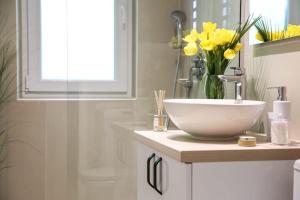 een badkamer met een wastafel en een vaas met gele bloemen bij Brasov Studio in Braşov