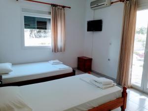 a room with two beds and a tv and a window at Giannis Studios in Nikiana