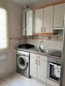 een keuken met een wastafel en een wasmachine bij APARTAMENTO HUESCA in Huesca