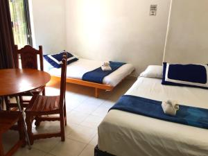 Habitación con 2 camas, mesa y silla en Villa Costa Chica Comodisimo piscina gigante jardines, en Acapulco